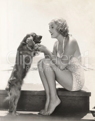 Young woman playing with Cocker Spaniel at beach