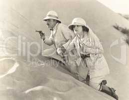 Armed couple climbing up sand dune