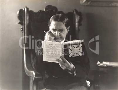 Man closely studying a crossword puzzle book