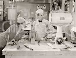 Butcher and customer looking at weight of chicken on scale