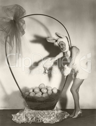Woman in bunny costume with large basket of Easter eggs