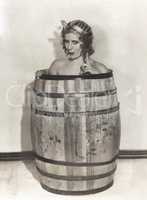 Naked woman sitting in wooden barrel