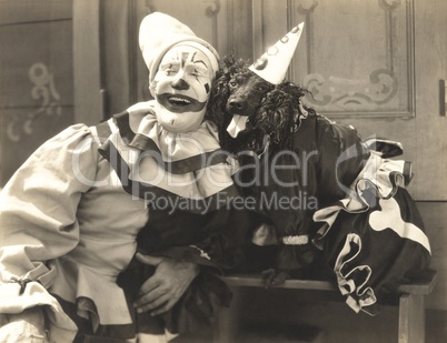 Clown posing with dog dressed in clown costume