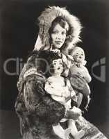 Women wearing Eskimo fur coat holding dolls