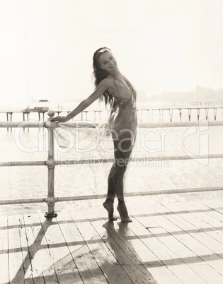 Woman in bathing suit on tiptoes posing on pier