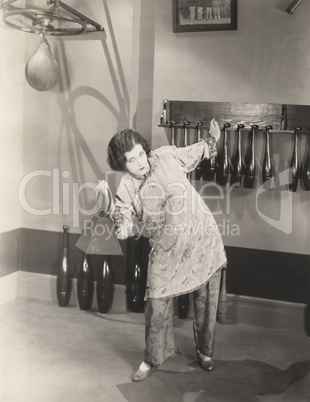 Determined woman in silk pajamas lifting weights in gym