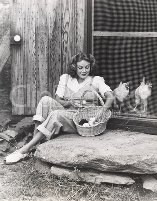 Woman collecting eggs from chickens