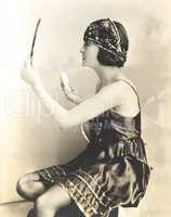 Side view of young woman holding powder puff and mirror
