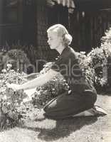 Full length side view of young woman pruning plants in garden