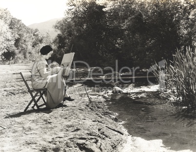 Portrait of a female artist painting by the river