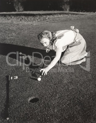 Female golfer crouching to line up a shot