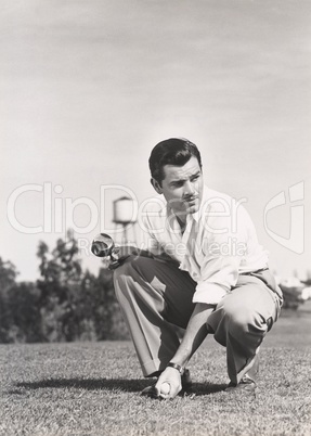 Golfer crouching on golf course