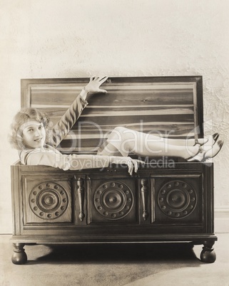 Woman sitting in wooden chest