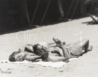 Happy couple sunbathing on beach