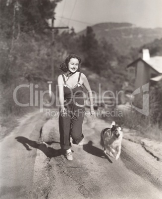 Woman running on dirt road with her dog