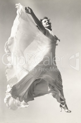 Low angle view of woman in gown jumping in mid-air