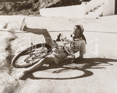 Woman falling off her bicycle on side of road