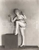 Dancer posing with her leg up on large wooden block