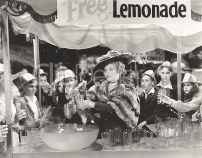 Woman giving out free lemonade to children at fair