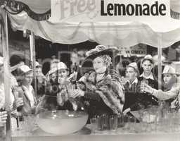 Woman giving out free lemonade to children at fair