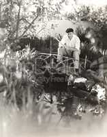 Man sitting on footbridge fishing in pond