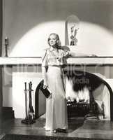 Woman in silk gown standing in front of fireplace