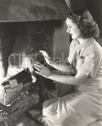 Woman warming her hands by the fireplace