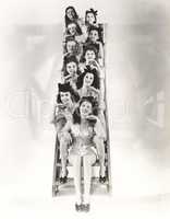 Ten chorus girls sitting on a ladder