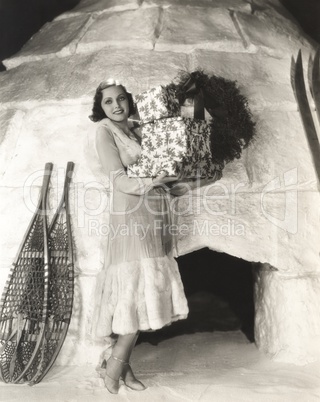 Woman carrying gift boxes outside igloo