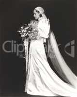 Side view of elegant bride holding bouquet against black background
