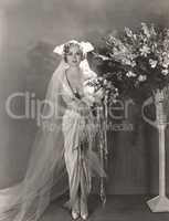 Bride standing next to tall vase of flowers