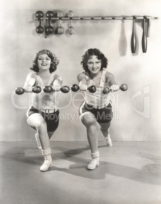 Two women exercising with dumbbells at gym