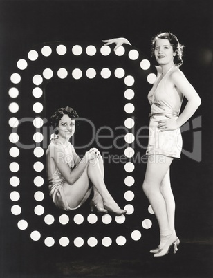 Two models posing by large letter O