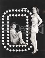 Two models posing by large letter O