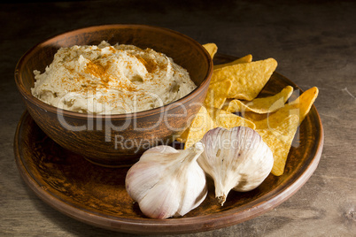 Hummus in an earthenware dish and garlic
