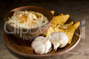 Hummus in an earthenware dish and garlic