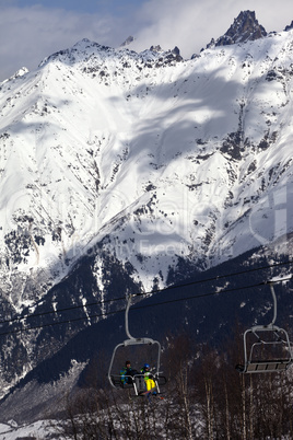 Skiers on ski lift in winter sun mountains