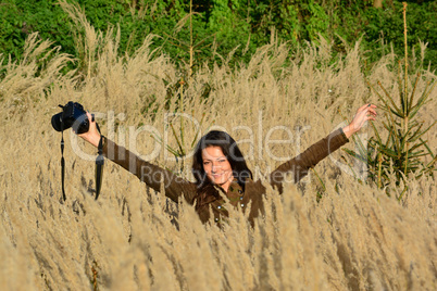 Cheerful, young brunette with DSLR in autumn meadow