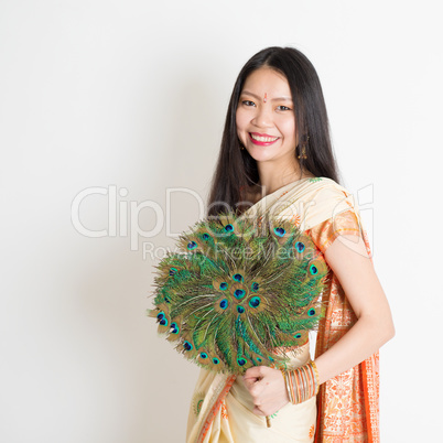 Young girl with peacock feather fan in Indian sari dress