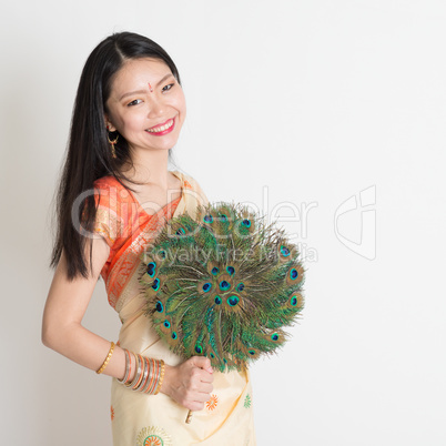 Young female with peacock feather fan in Indian sari dress