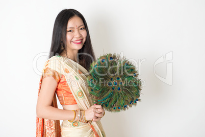Young woman with peacock feather fan in Indian sari dress