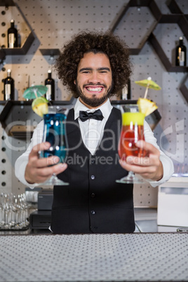 Bartender holding two glass of cocktail in bar counter