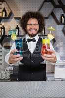 Bartender holding two glass of cocktail in bar counter