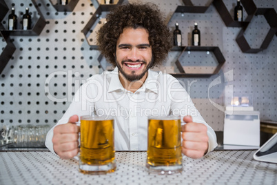 Bartender holding two glass of beer in bar counter