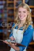 Smiling female staff writing on clipboard in supermarket