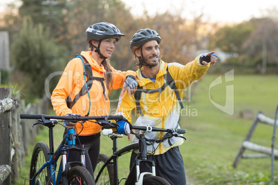 Biker couple with mountain bike pointing in distance