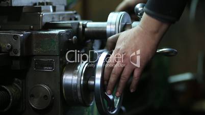 Worker controls adjustment wheel of lathe machine