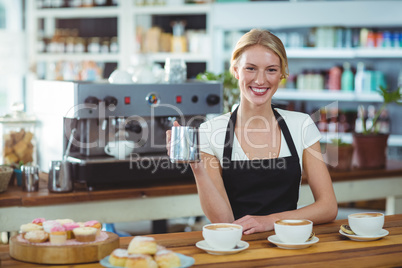 Portrait of waitress making cup of coffee at counter