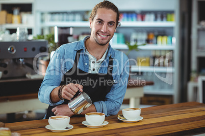 Portrait of waiter making cup of coffee at counter