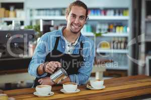 Portrait of waiter making cup of coffee at counter